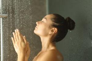 一个女人把手放在温暖的淋浴水中